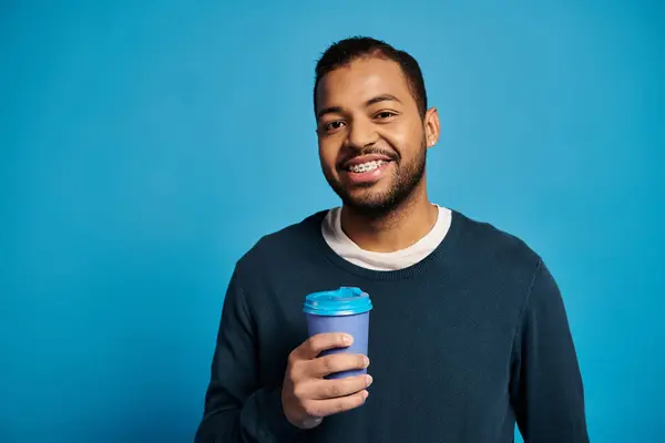 Portrait of charming african american young man looking to camera with paper cup in hand — Stock Photo