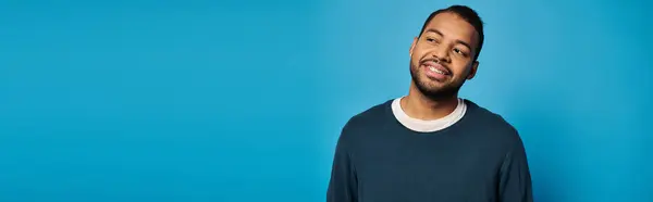 Striscione di attraente uomo afro-americano nei suoi 20 anni cercando di lato contro sfondo blu — Foto stock