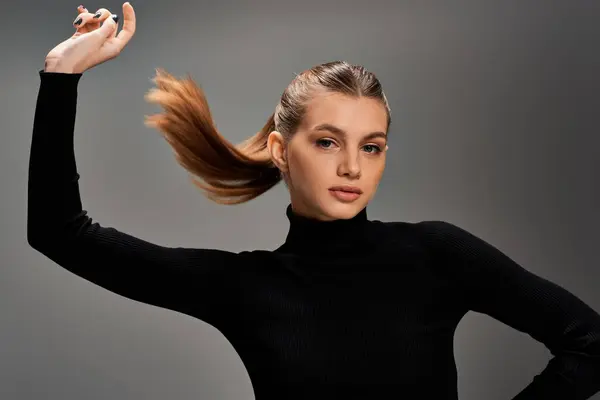 Una hermosa mujer en un top negro jugando elegantemente con su pelo largo. - foto de stock