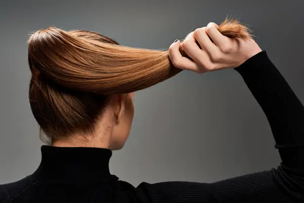Une jeune femme respire l'élégance avec ses cheveux coiffés dans une queue de cheval élégante, mettant en valeur sa beauté classique. — Photo de stock