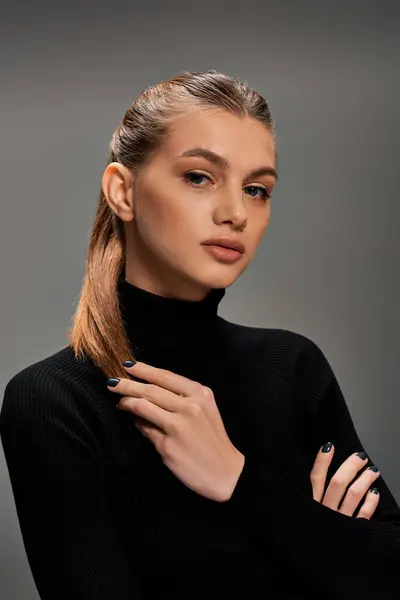 Молода жінка з довгим волоссям виявляє вишуканість у чорному светрі з черепашками, демонструючи класичний і вічний стиль. — стокове фото