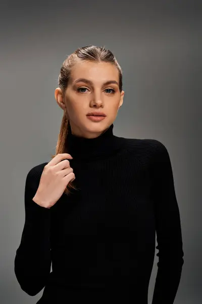 Eine zierliche junge Frau mit langen Haaren trägt einen stylischen schwarzen Rollkragenpullover. — Stockfoto