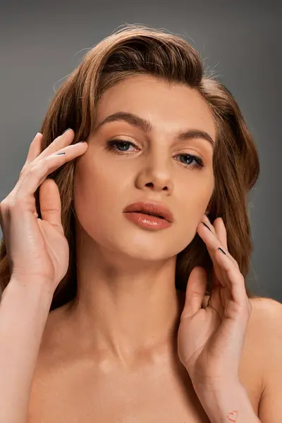 Eine junge Frau mit langen welligen Haaren hält ihre Hände in einer gelassenen Geste vor ihr Gesicht. — Stockfoto