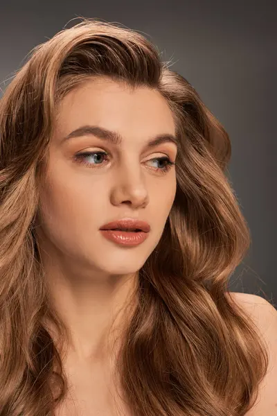 Una mujer joven con el pelo largo y ondulado castaño y ojos cautivadores se ve encantadora, pancarta - foto de stock