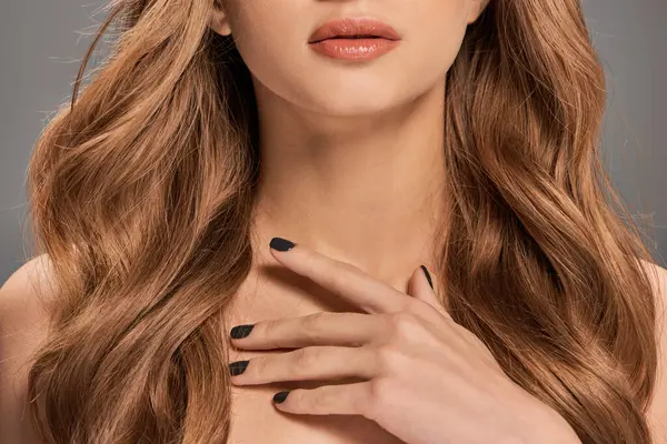 Una joven con el pelo castaño largo muestra su elegancia con uñas negras llamativas, exudando misterio y sofisticación. - foto de stock