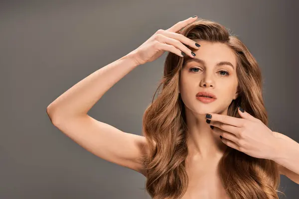 Uma jovem com cabelos longos e ondulados segura delicadamente o cabelo nas mãos, mostrando um momento de intimidade e beleza. — Fotografia de Stock