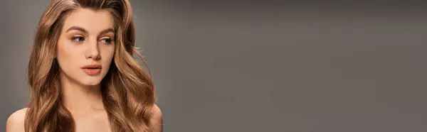 Una joven y hermosa mujer con el cabello castaño ondulado largo contornea sus rasgos en una expresión humorística, pancarta - foto de stock