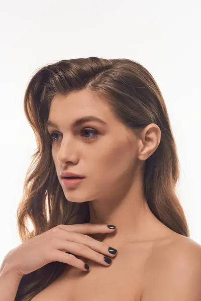 Eine junge Frau mit langen welligen Haaren elegant auf grauem Hintergrund — Stockfoto
