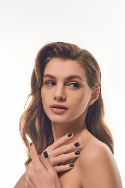 A stunning young woman with long wavy hair showcases her black manicure in a chic and stylish pose. — Stock Photo