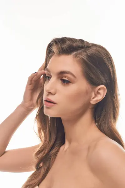 Una giovane bella donna con lunghi capelli ondulati che colpisce una posa, trasudando fiducia ed eleganza. — Foto stock