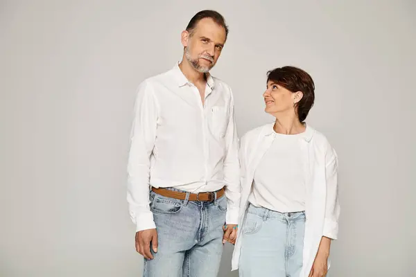 Porträt einer Frau, die sich an den Händen hält und den Mann mit Liebe ansieht und ihn auf grauem Hintergrund umarmt — Stockfoto