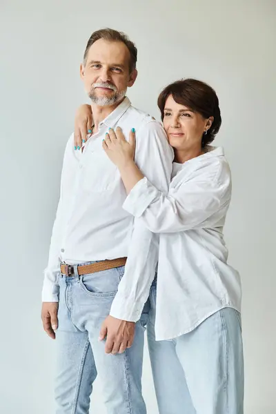 Portrait of middle aged beautiful stylish couple hugging and smiling on grey background — Stock Photo