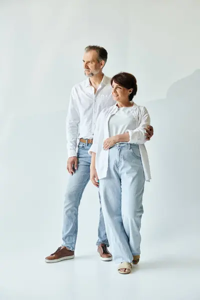 Full length image of mature beautiful couple standing on grey background, looking away — Stock Photo