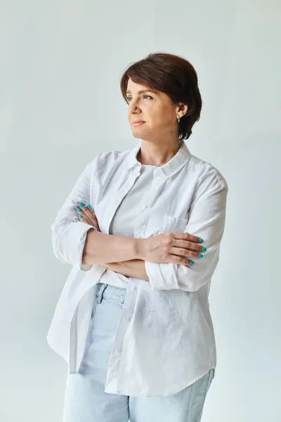 Porträt einer reifen schönen Frau, die mit verschränkten Armen dasteht und wegschaut — Stockfoto