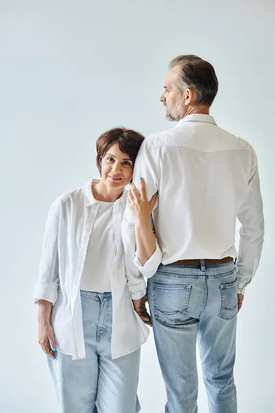 Attractive middle aged woman hugging mature man by hand with love on grey background — Stock Photo