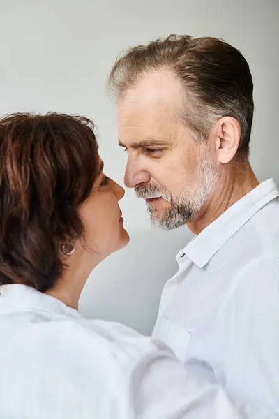 Side view portrait of mature couple in love hugging and going to kiss on grey backdrop, closeness — Stock Photo