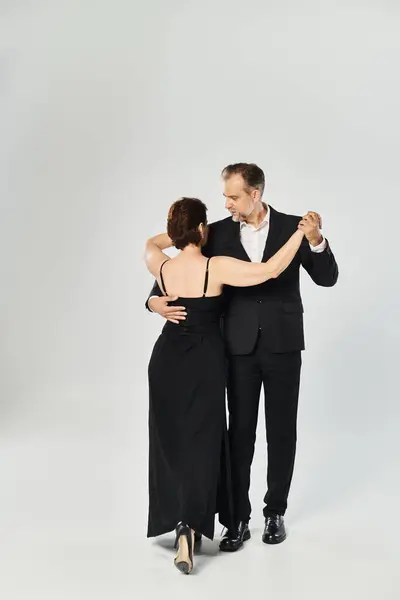Danse de salon couple d'âge moyen dans une pose de danse et souriant isolé sur fond gris — Photo de stock