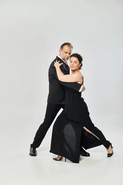 Side view shot of mature attractive couple in a tango dance pose isolated on grey background — Stock Photo