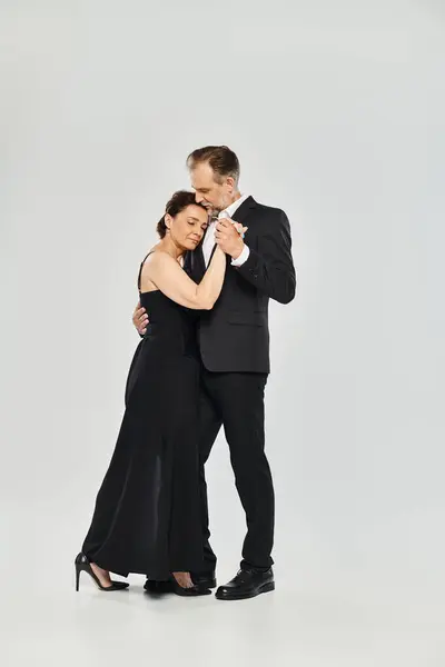 Tiro de comprimento total de casal atraente maduro em uma pose de dança de tango isolado em fundo cinza — Fotografia de Stock