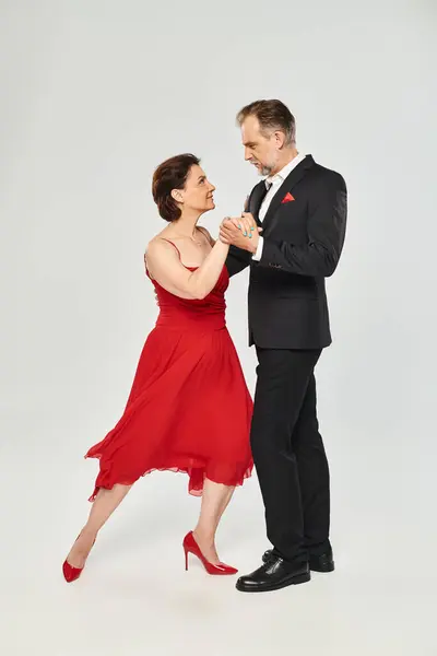 Prise de vue pleine longueur d'un beau couple mature dans une pose de tango isolé sur fond gris — Photo de stock
