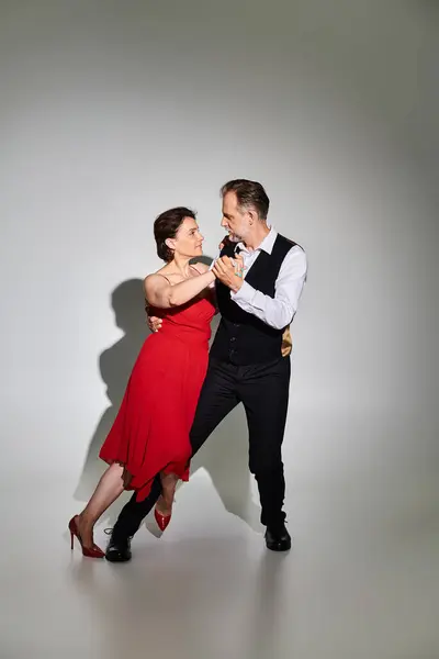 Image de couples matures danseurs de tango en robe rouge et costume performant sur fond gris — Photo de stock
