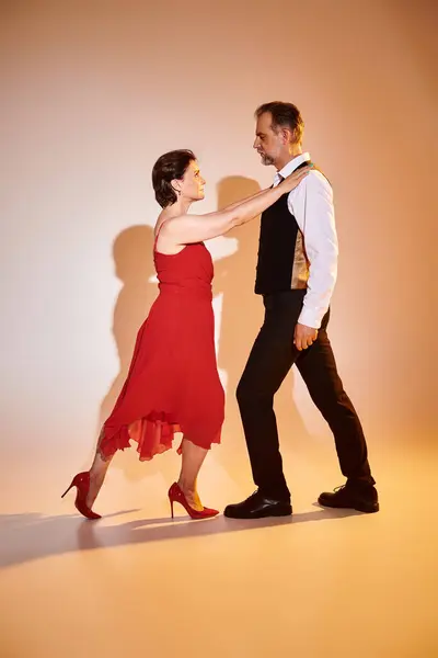 Imagem de dançarinos de tango casal maduro em vestido vermelho e terno realizando em fundo cinza — Fotografia de Stock