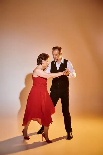 Ballroom dança casal de meia idade em vestido vermelho e terno dança tango isolado no fundo cinza — Fotografia de Stock