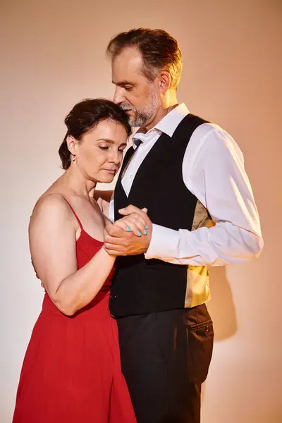 Side view of mature attractive smiling couple dancing ballroom dance isolated on grey background — Stock Photo