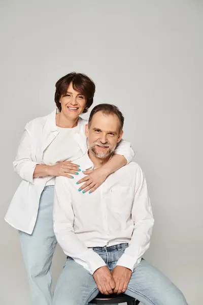 Porträt eines Mannes und einer Frau mittleren Alters, die in die Kamera blicken und auf grauem Hintergrund lächeln — Stockfoto