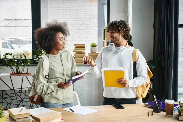 A man and a woman of different cultural backgrounds stand together in a modern office space, engaged in meaningful conversation. — Stock Photo