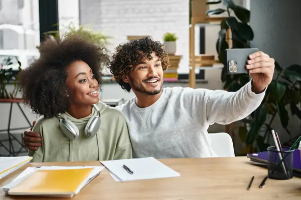 Un homme et une femme saisissent un moment, souriant ensemble tout en prenant un selfie dans un cadre de bureau moderne. — Photo de stock