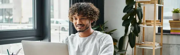 Indian man is deeply engaged in work on his laptop computer in a modern coworking space. — Stock Photo