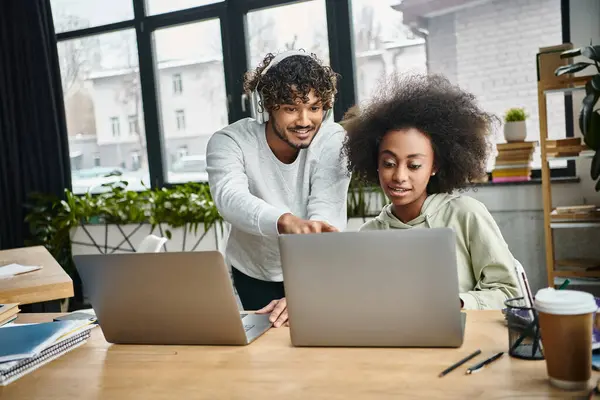 Un homme et une femme, immergés dans leur travail, se concentrent passionnément sur un écran d'ordinateur portable dans un espace de coworking moderne. — Photo de stock