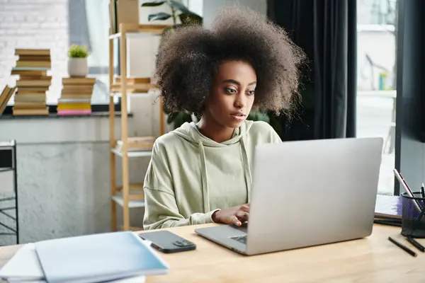 A multicultural woman engrossed in work, seated in front of her laptop computer in a modern coworking space. — Stock Photo