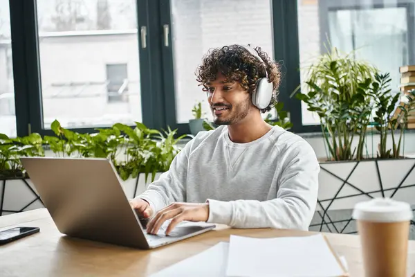 Um homem de fundo diversificado senta-se focado na frente de um laptop em um espaço de co-trabalho moderno. — Fotografia de Stock