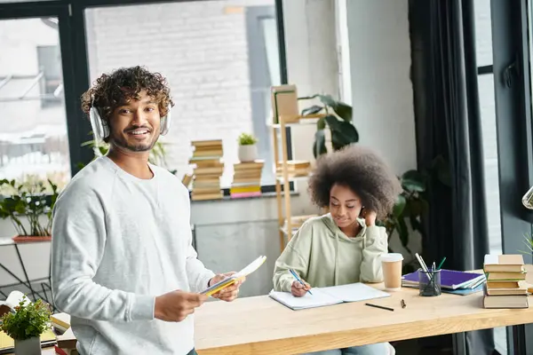 Un homme et une femme se tiennent côte à côte à un bureau dans un espace de coworking moderne, engagés dans une étude collaborative à l'aide d'appareils électroniques. — Photo de stock