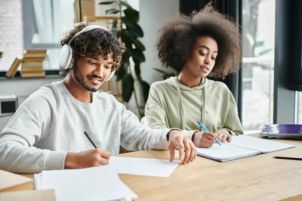 Ein Mann und eine Frau unterschiedlicher ethnischer Zugehörigkeit sitzen an einem Tisch und konzentrieren sich auf Papierkram und die Zusammenarbeit in einem modernen Coworking Space. — Stockfoto