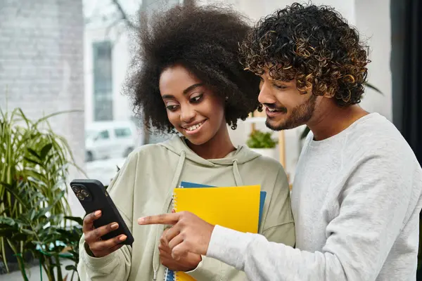 Ein multikultureller Mann und eine multikulturelle Frau, die in einem modernen Coworking Space Inhalte auf einem Handy betrachten. — Stockfoto