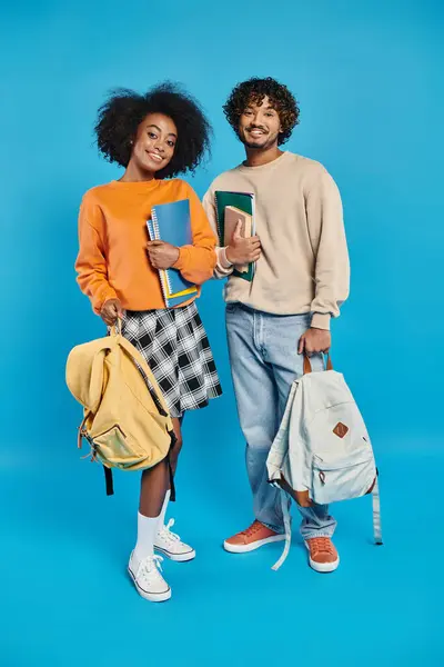 Una pareja interracial de estudiantes con atuendo casual de pie juntos. - foto de stock