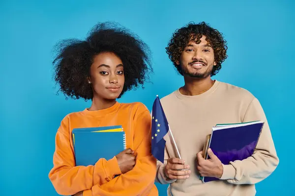 An interracial man and woman stand holding books, and EU flag, showcasing their love for literature — Stock Photo