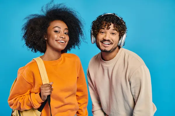 Un homme et une femme interracial se tiennent côte à côte sur un fond bleu, mettant en valeur l'unité et la convivialité. — Photo de stock