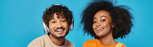 An interracial couple standing together in a studio, wearing headphones, immersed in the music they are listening to. — Stock Photo