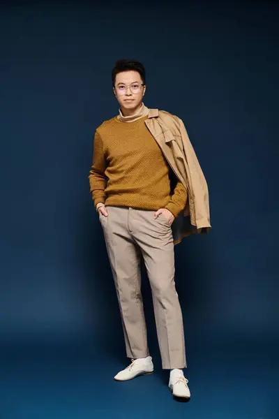 A fashionable young man poses confidently in a tan sweater and khaki pants, exuding elegance and style. — Stock Photo