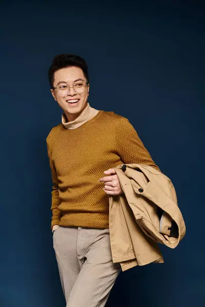 Модний молодий чоловік виділяє елегантність в коричневому светрі і засмаглих штанях, впевнено позує на камеру. — стокове фото