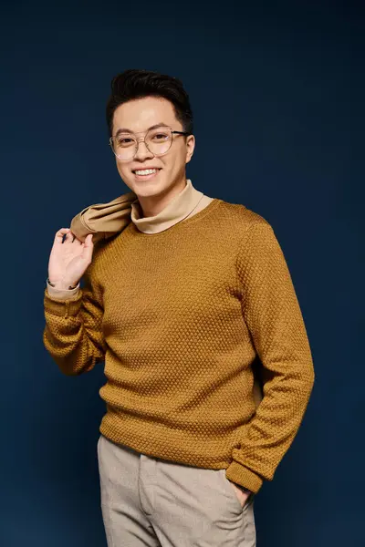 Um jovem na moda em óculos e uma camisola confiantemente posa para a câmera. — Fotografia de Stock