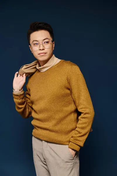 Um jovem na moda em óculos e uma camisola confiantemente posa para um quadro. — Fotografia de Stock