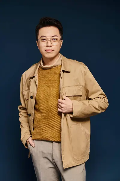 Um jovem elegante confiantemente posa em uma jaqueta bronzeada e óculos, exalando elegância e charme. — Fotografia de Stock