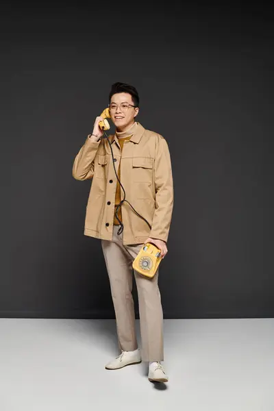 Un joven de moda con un atuendo elegante, utilizando activamente un teléfono celular para hacer una llamada. - foto de stock