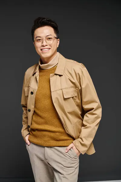 A stylish young man wearing glasses and a tan jacket poses elegantly in this vibrant portrait. — Stock Photo