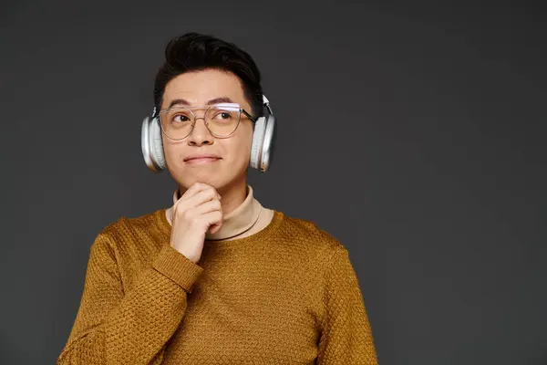 Un joven de moda con auriculares y un suéter, exudando elegancia y estilo mientras escucha música. - foto de stock